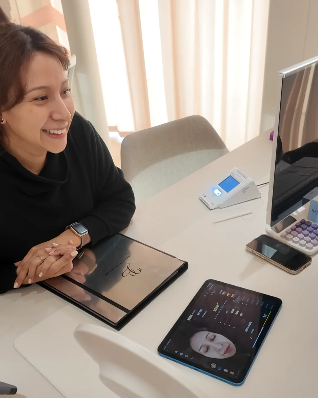 相談テーブルで微笑む女性と、顔の分析画面が表示されたタブレット、手鏡