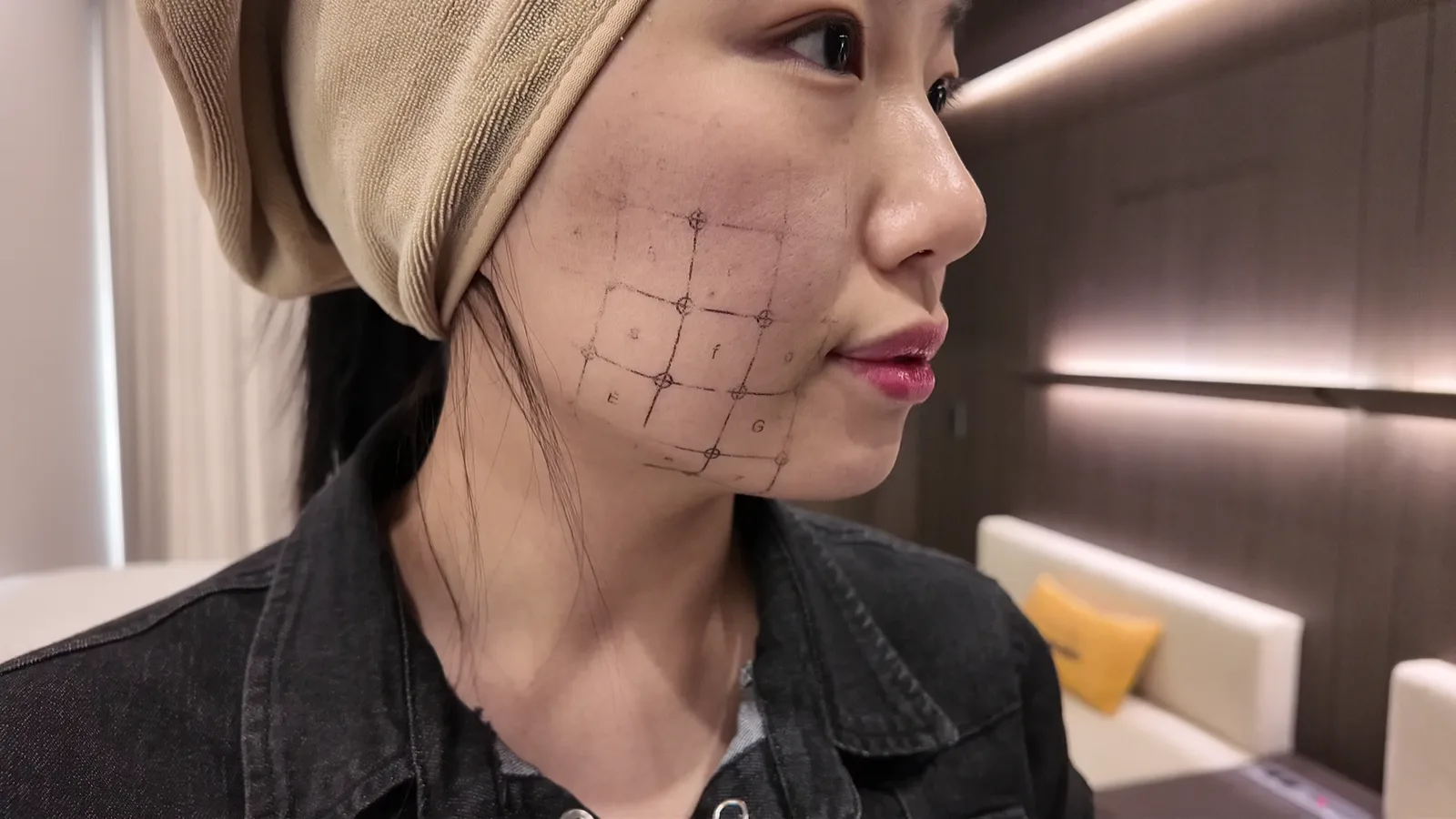 사각 격자가 그려진 볼과 턱선을 옆에서 본 모습, 수건 헤어밴드를 한 사람이 옆을 보고 있음