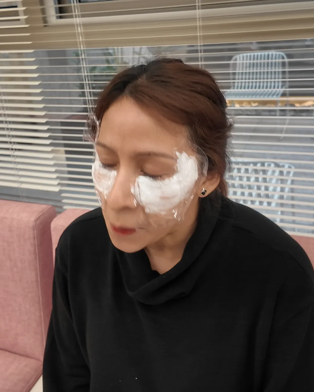 両目の周りに白いクリームを塗って座っている女性